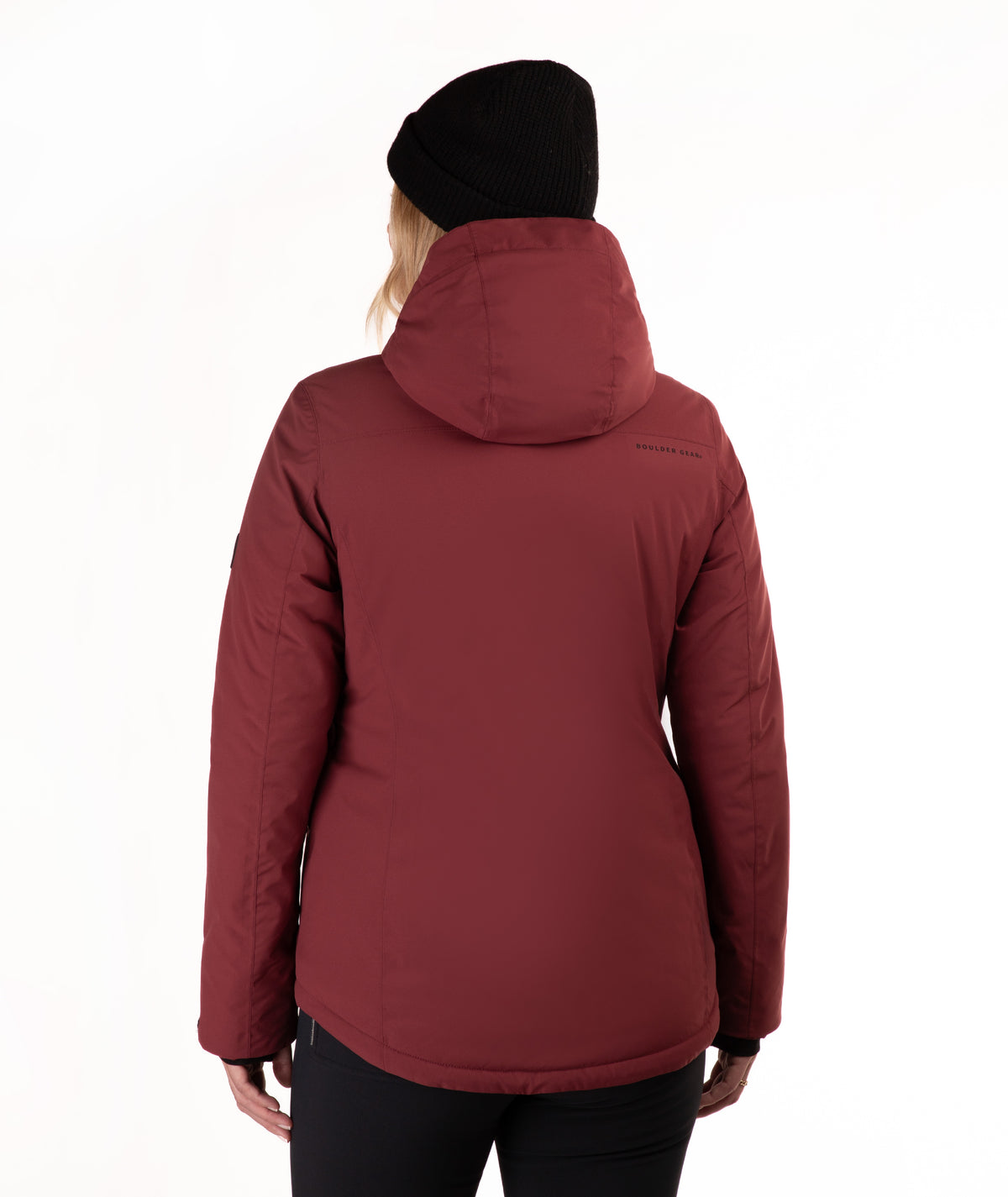 A woman viewed from the back wearing a dark red hooded puffer jacket, a black beanie, and black pants against a plain white background.