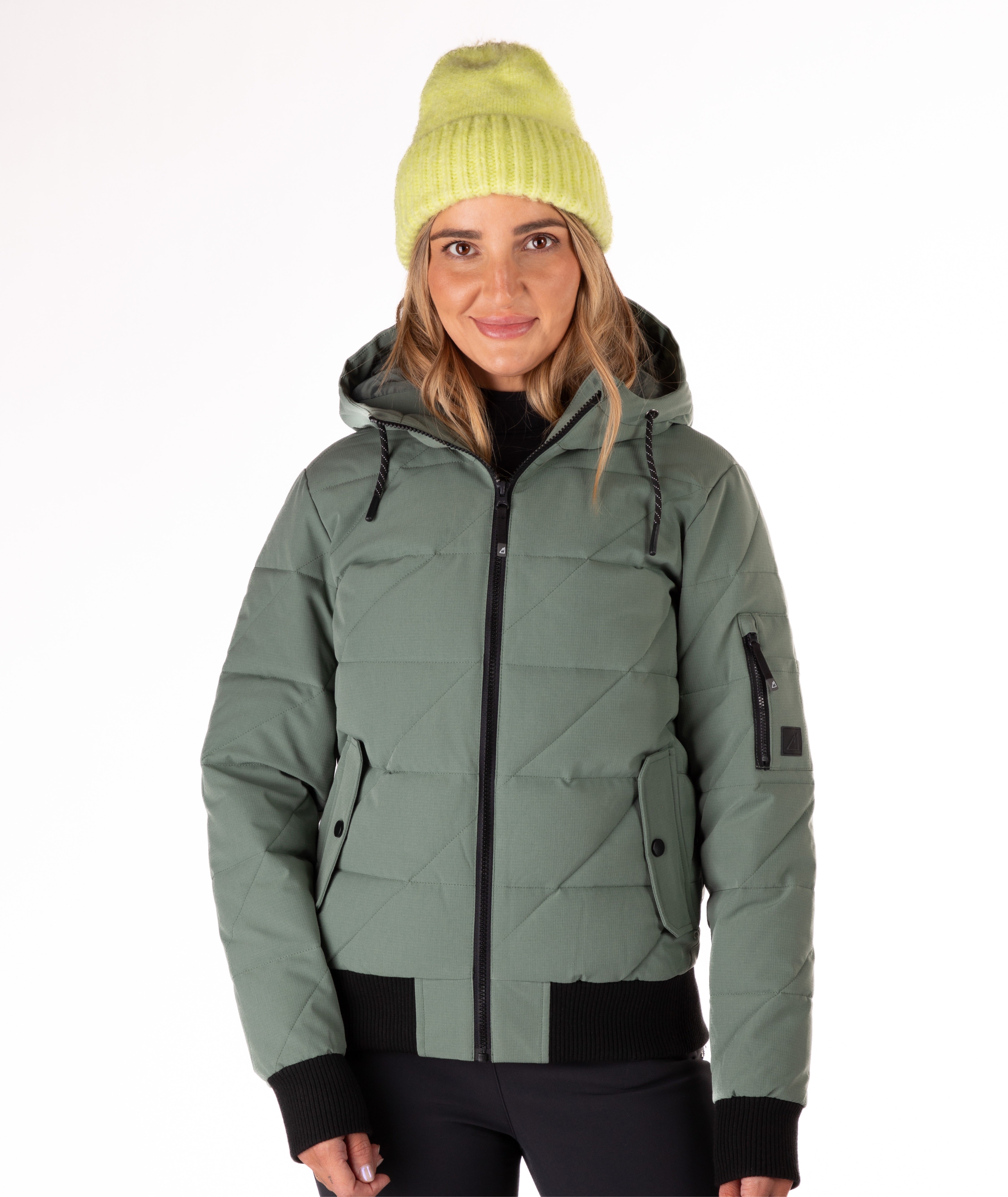 Person wearing a green quilted jacket with a hood and black knit trim on wrist cuffs and hem on a white background