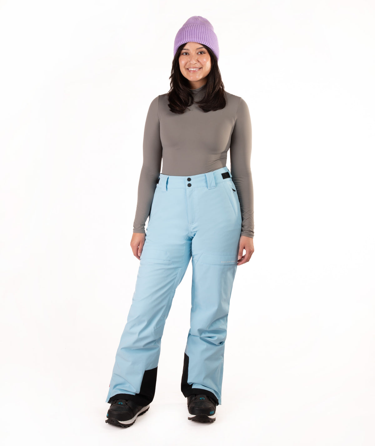 Person wearing light blue snow pants and a gray top with a white background