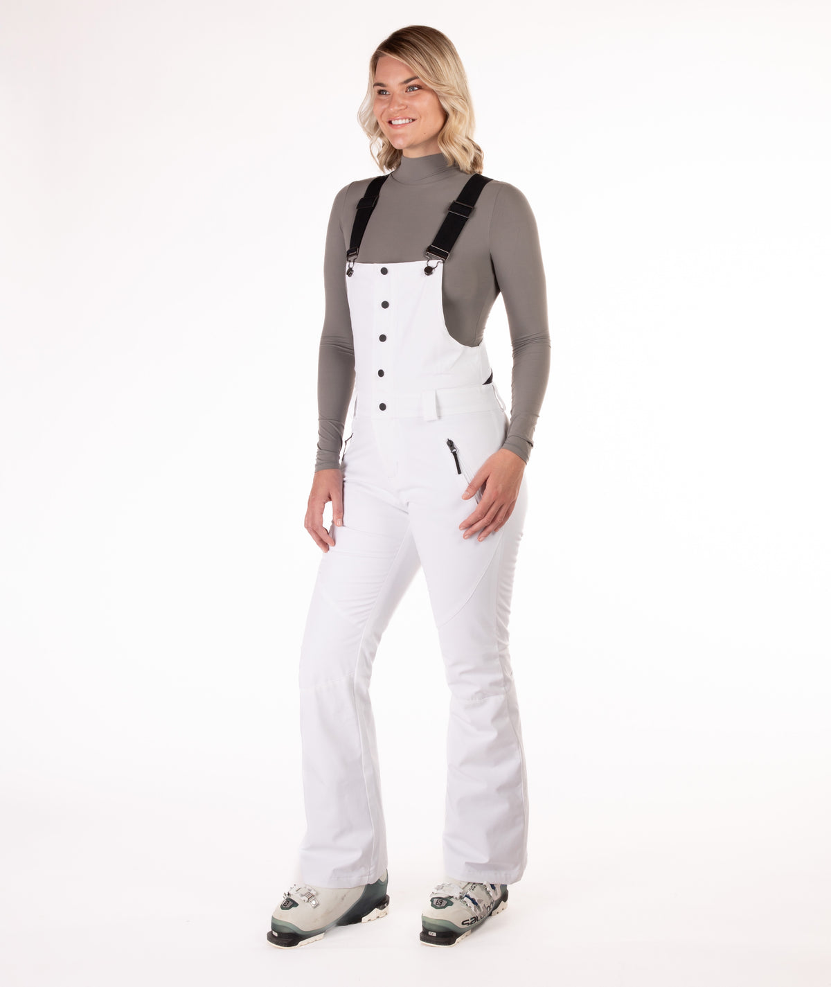 Person wearing a white snow bib overalls on a white background.