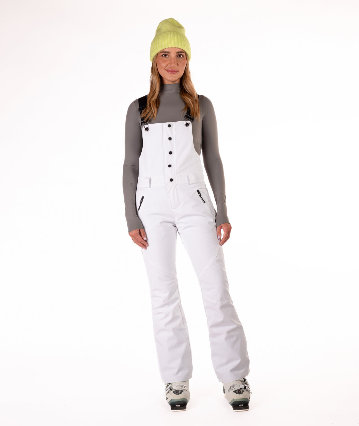 Person wearing a white snow bib overalls on a white background.