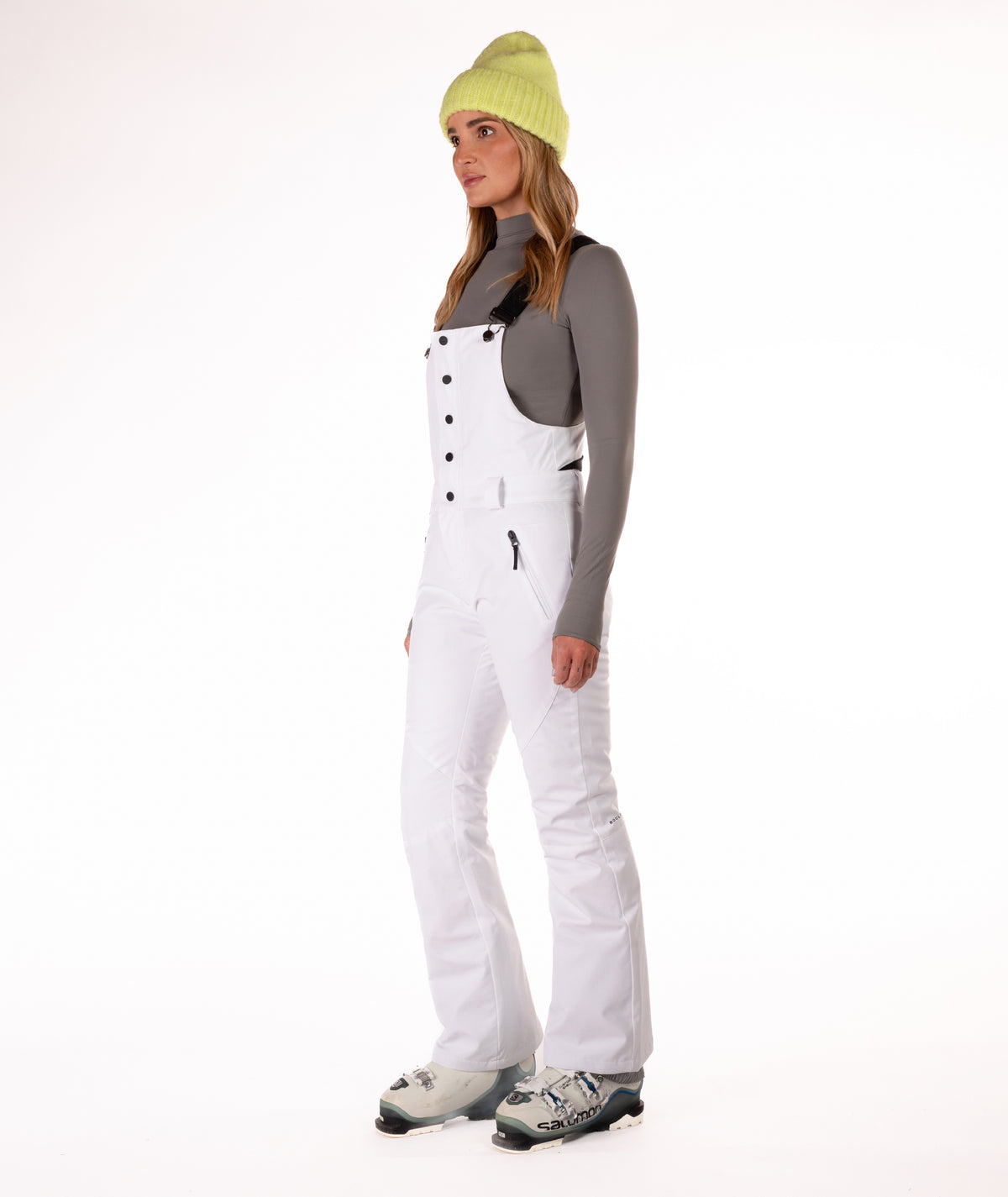 Person wearing a white snow bib overalls on a white background.