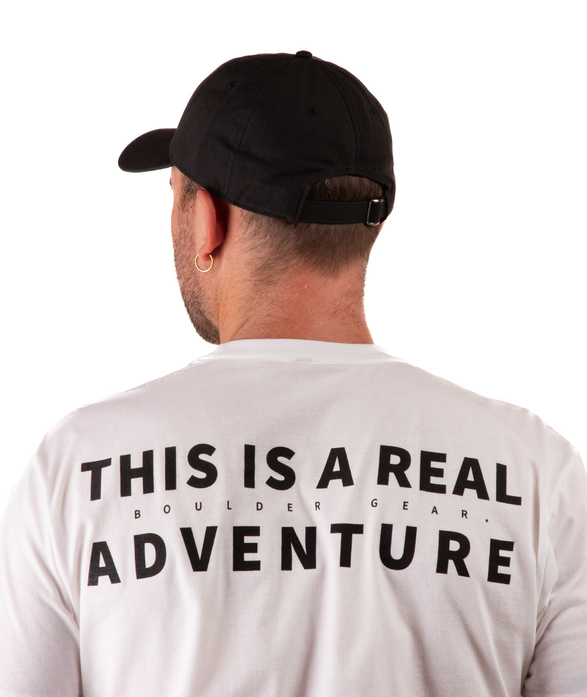 back of a Person wearing a white t-shirt with 'This is a Real Adventure' text on the back and a black cap, standing against a white background.