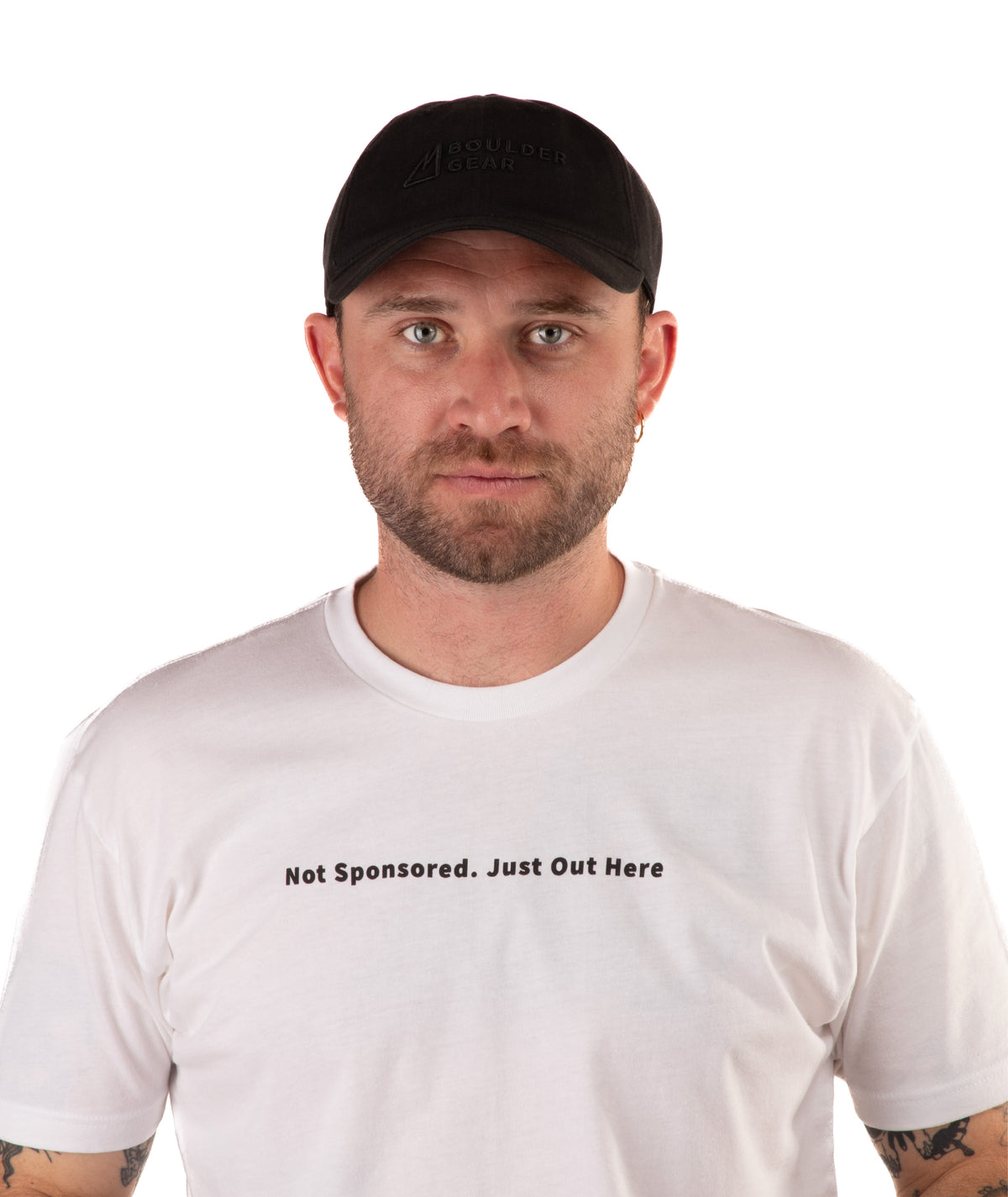 Man wearing a white t-shirt with text 'Not Sponsored. Just Out Here' with a black cap on a white background