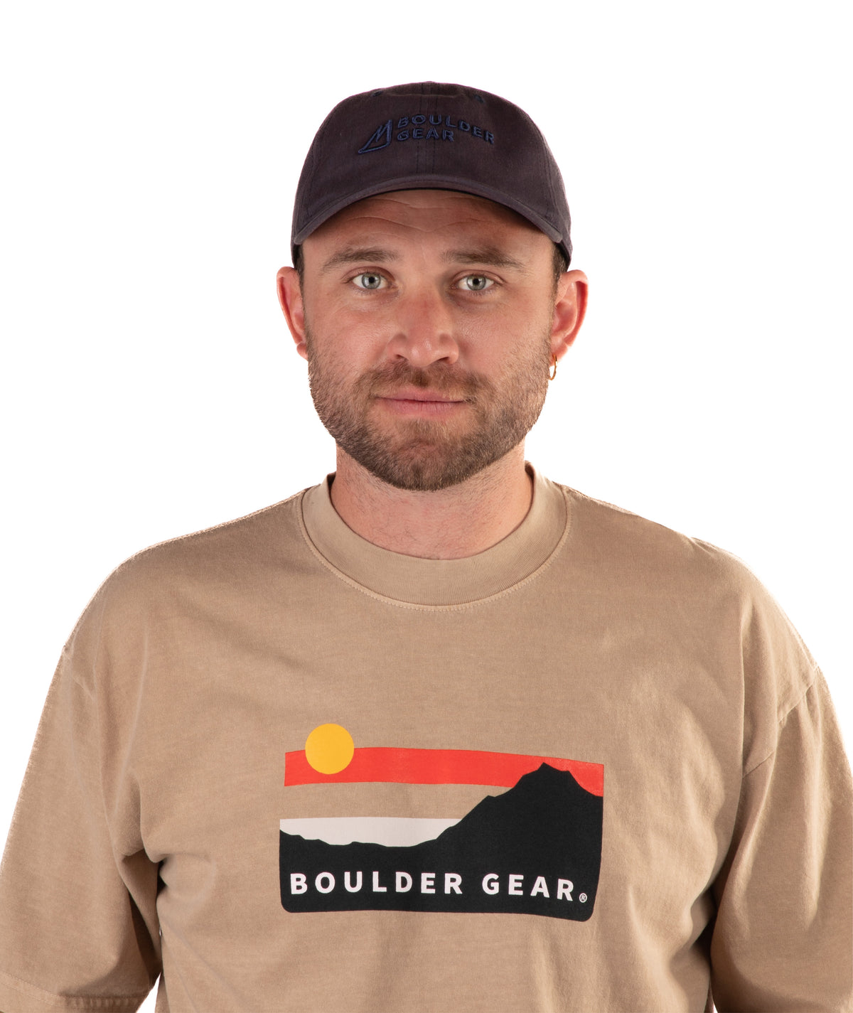 Man wearing a brown Boulder Gear t-shirt and navy cap on a white background