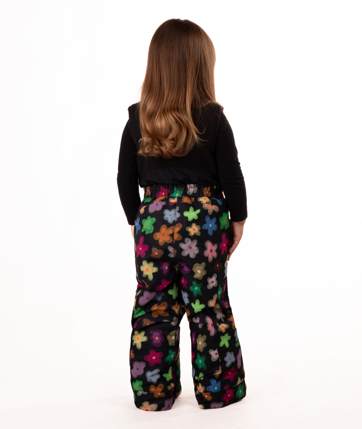 back of child wearing a multi color flower print snow bib with black top on a white background