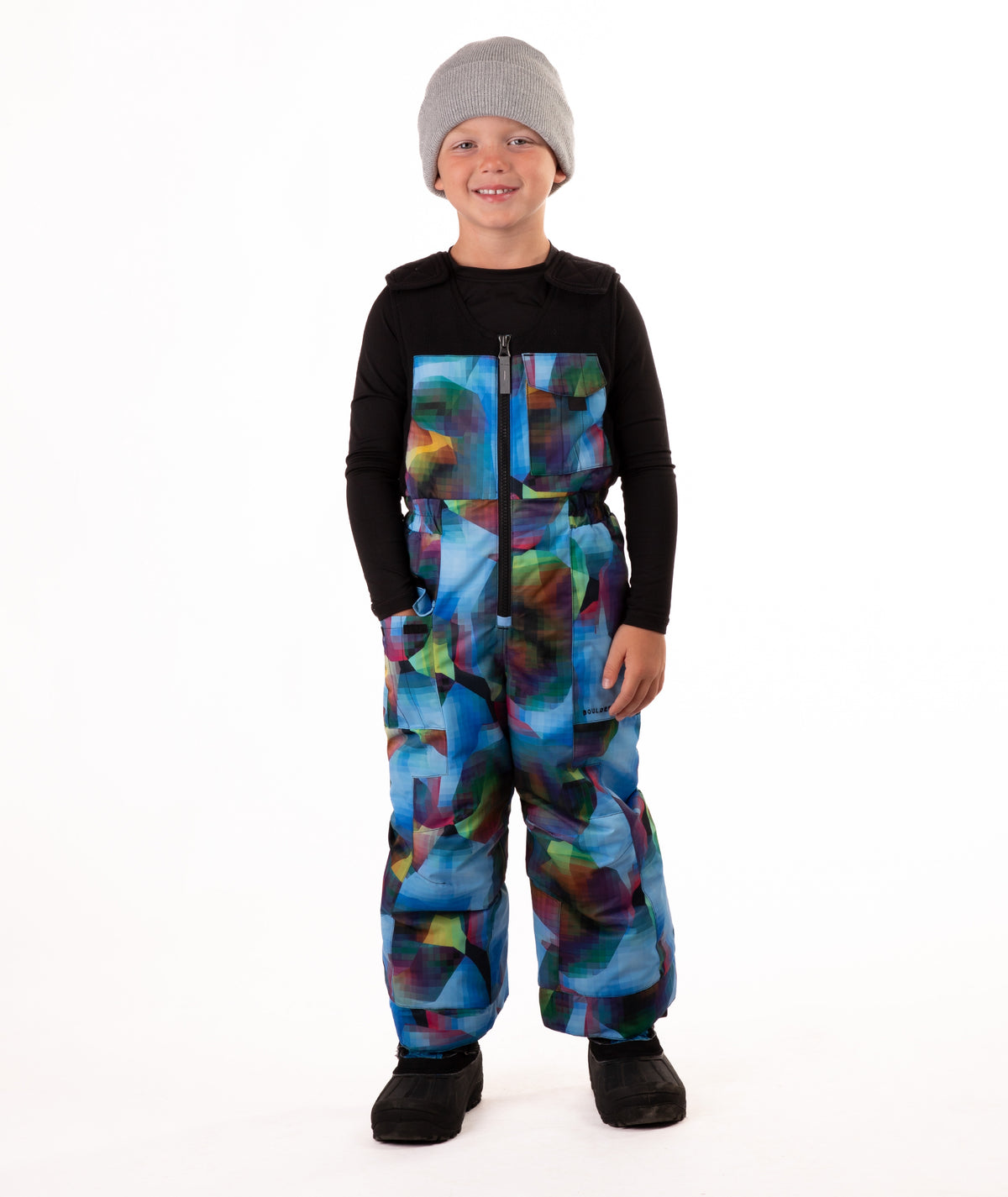 Child wearing colorful geometric print snow bibs on a white background