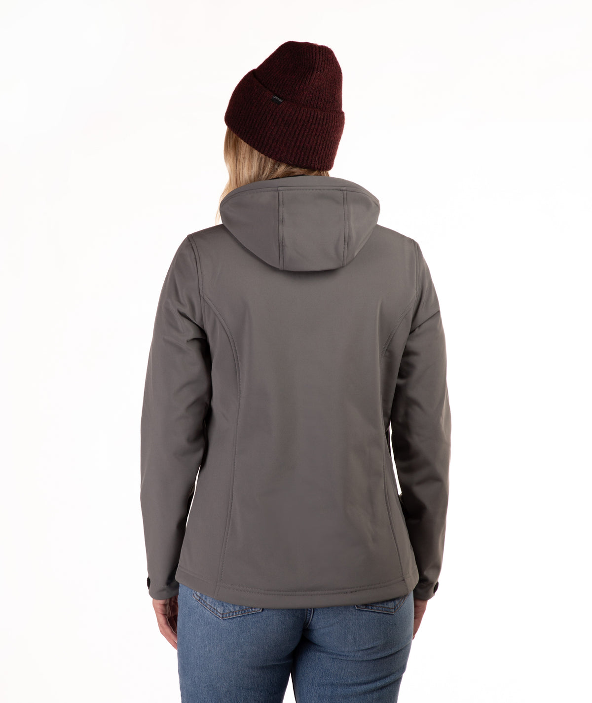 A woman viewed from the back wearing a dark gray hooded jacket, a burgundy knit beanie, and blue jeans against a plain white background.