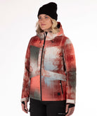Person wearing an abstract printed jacket in primarily rust, gray and beige with a white background
