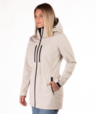 Woman wearing a beige winter coat with black zippers on a white background