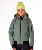 Person wearing a green quilted jacket with a hood and black knit trim on wrist cuffs and hem on a white background