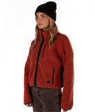 Person wearing a red fleece jacket with black zipper on a white background