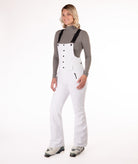 Person wearing a white snow bib overalls on a white background.