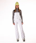 Person wearing a white snow bib overalls on a white background.