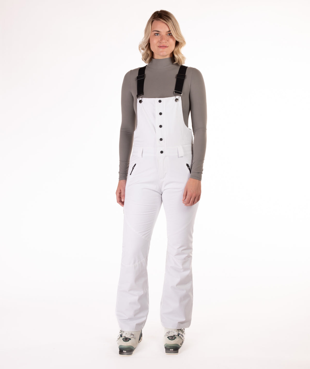 Person wearing a white snow bib overalls on a white background.