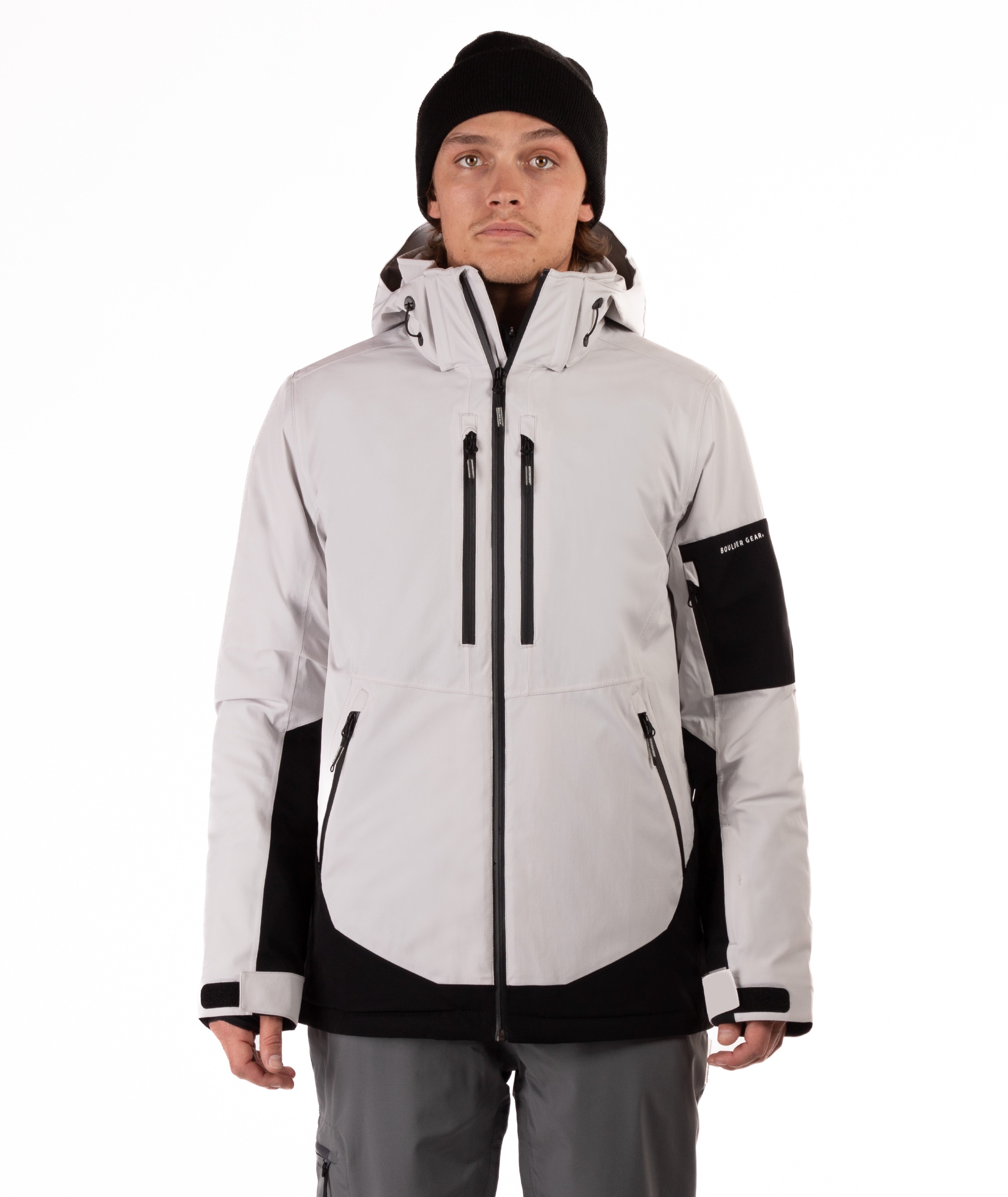 Person wearing a light gray and black jacket with a hood on a white background