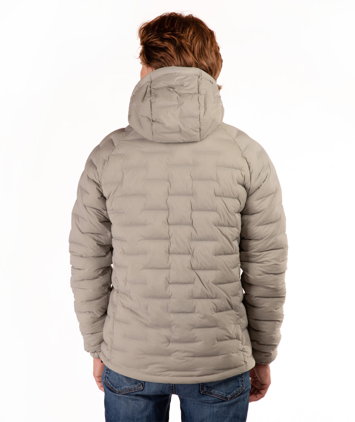 A person viewed from the back wearing a light taupe quilted puffer jacket with a hood, paired with blue jeans, against a plain white background.