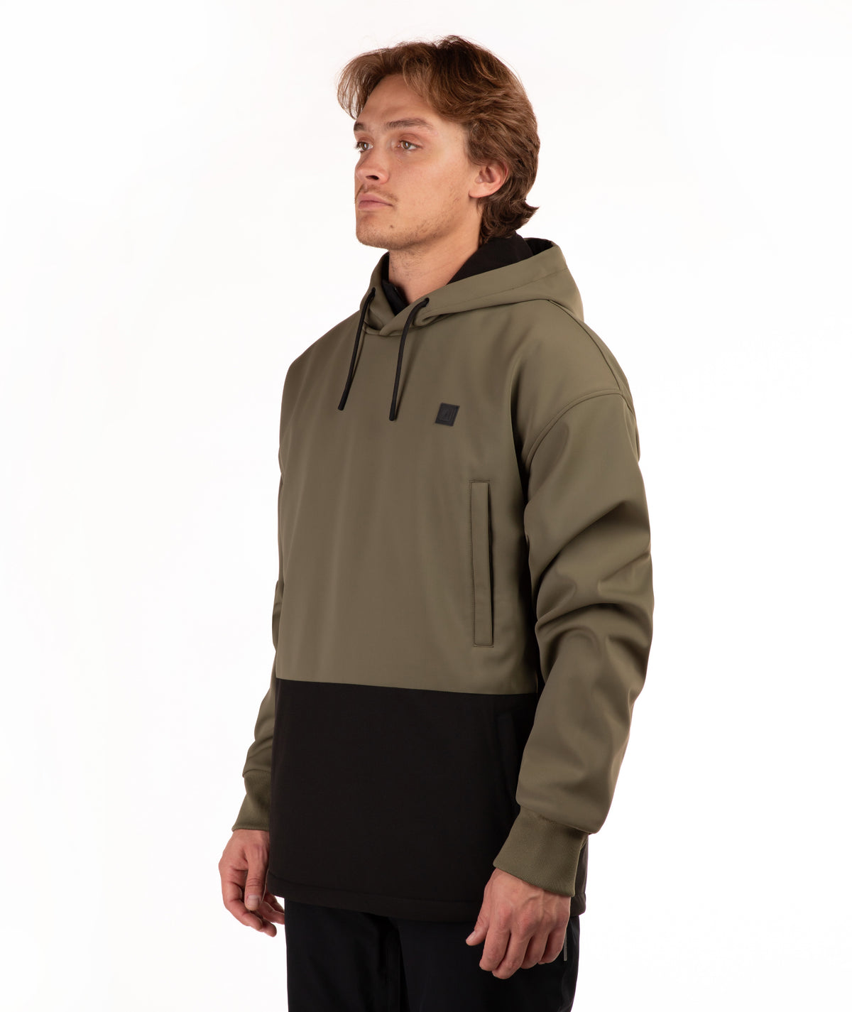 A man wearing a color-blocked pullover hoodie with an olive green upper section and a black lower section, standing against a plain white background.