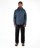 Man wearing a blue raincoat and black rain pants on a white background
