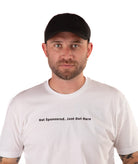 Man wearing a white t-shirt with text 'Not Sponsored. Just Out Here' with a black cap on a white background