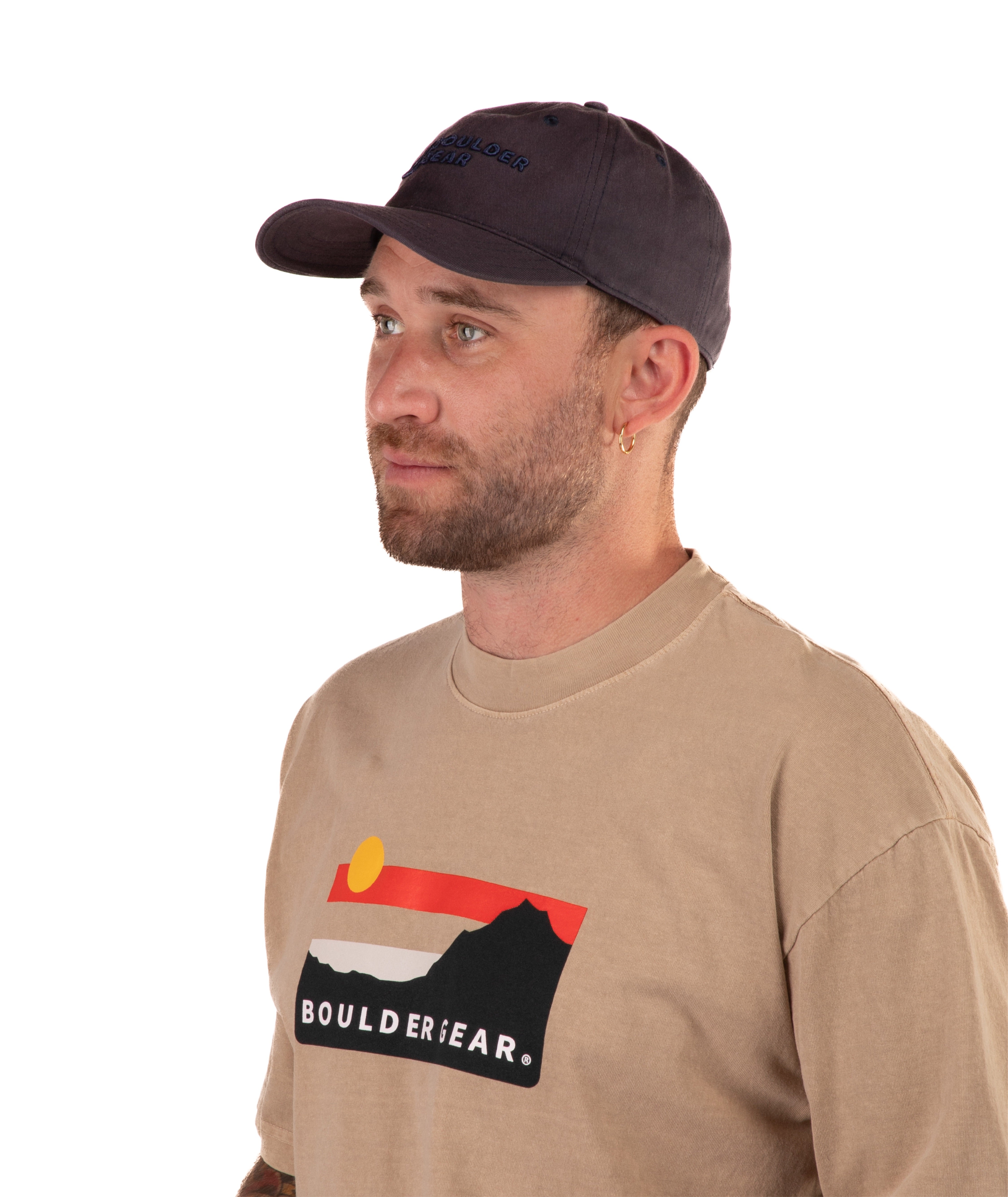 Man wearing a brown Boulder Gear t-shirt and navy cap on a white background
