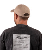back of a Man wearing a black Boulder Gear T-shirt and khaki cap on a white background