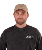 Man wearing a black Boulder Gear T-shirt and khaki cap on a white background