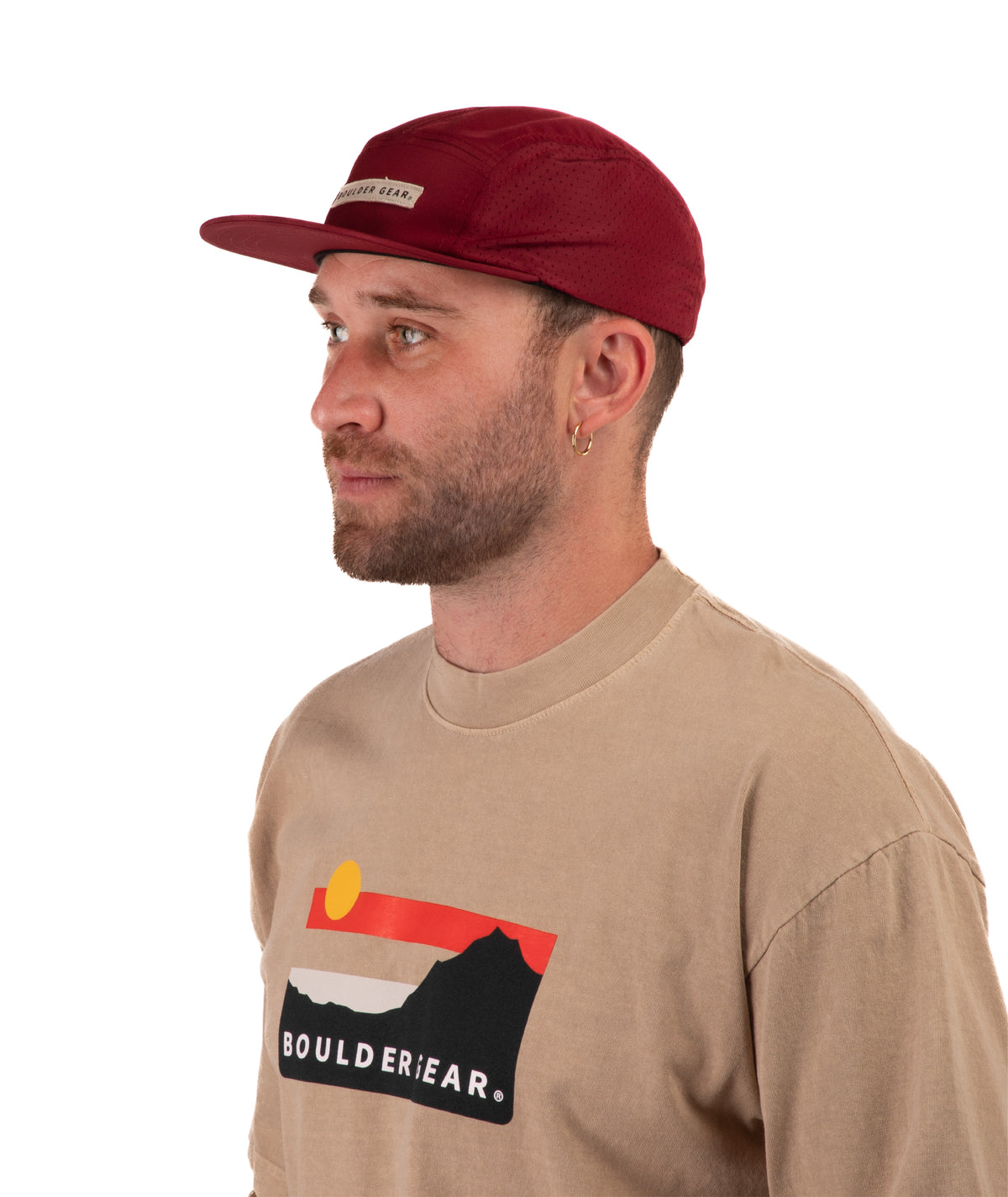 Man wearing a beige t-shirt with Boulder Gear logo and a maroon cap on a white background