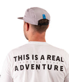 back of a Man wearing a white t-shirt with text and a gray cap on a white background