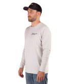 Man wearing a light gray long-sleeve shirt with a logo on a white background