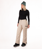Person wearing a black long-sleeve top and beige snow pants on a white background