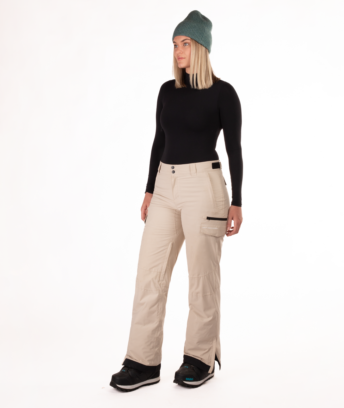 Person wearing a black long-sleeve top and beige snow pants on a white background