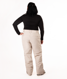 back of person wearing a black long-sleeve top and beige snow pants on a white background