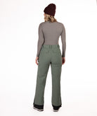 back of person wearing a gray long-sleeve top and green snow pants on a white background