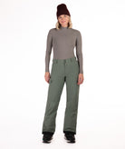 Person wearing a gray long-sleeve top and green snow pants on a white background