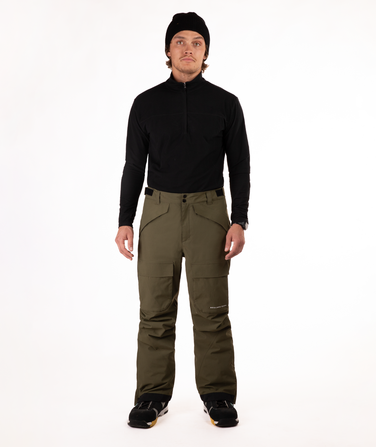 Person wearing a black shirt and green snow pants on a white background