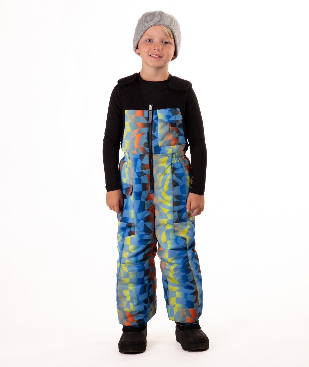 Child wearing colorful geometric print snow bibs on a white background