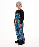 Child wearing colorful geometric print snow bibs on a white background
