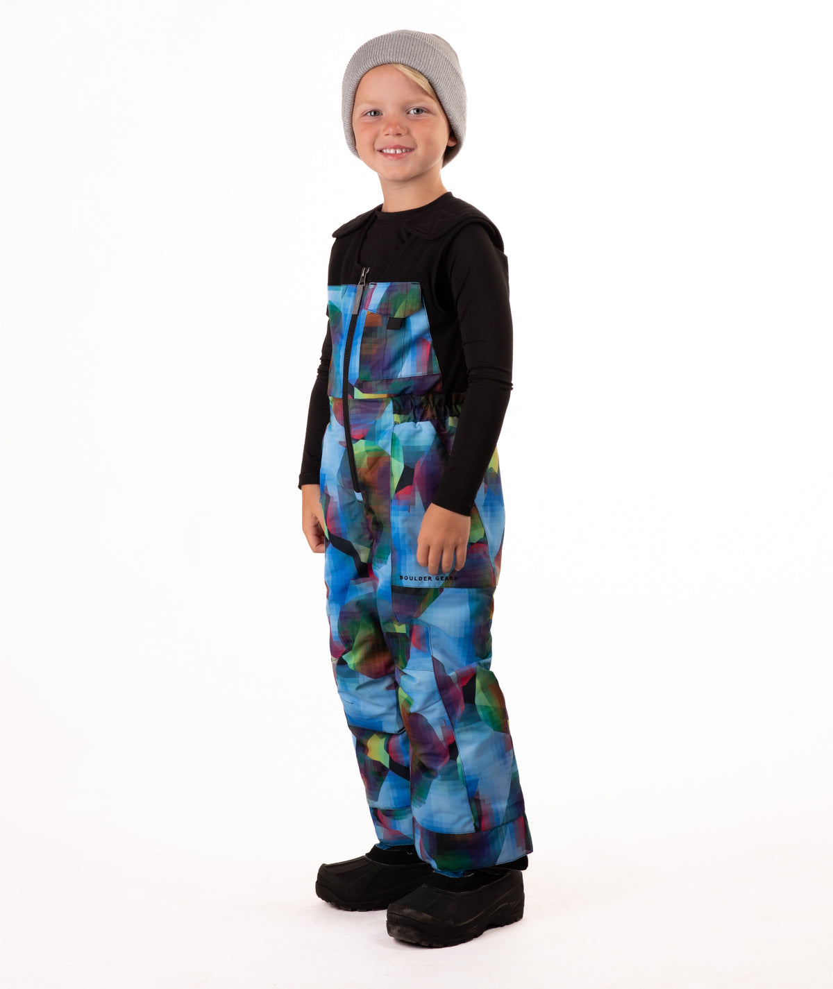 Child wearing colorful geometric print snow bibs on a white background