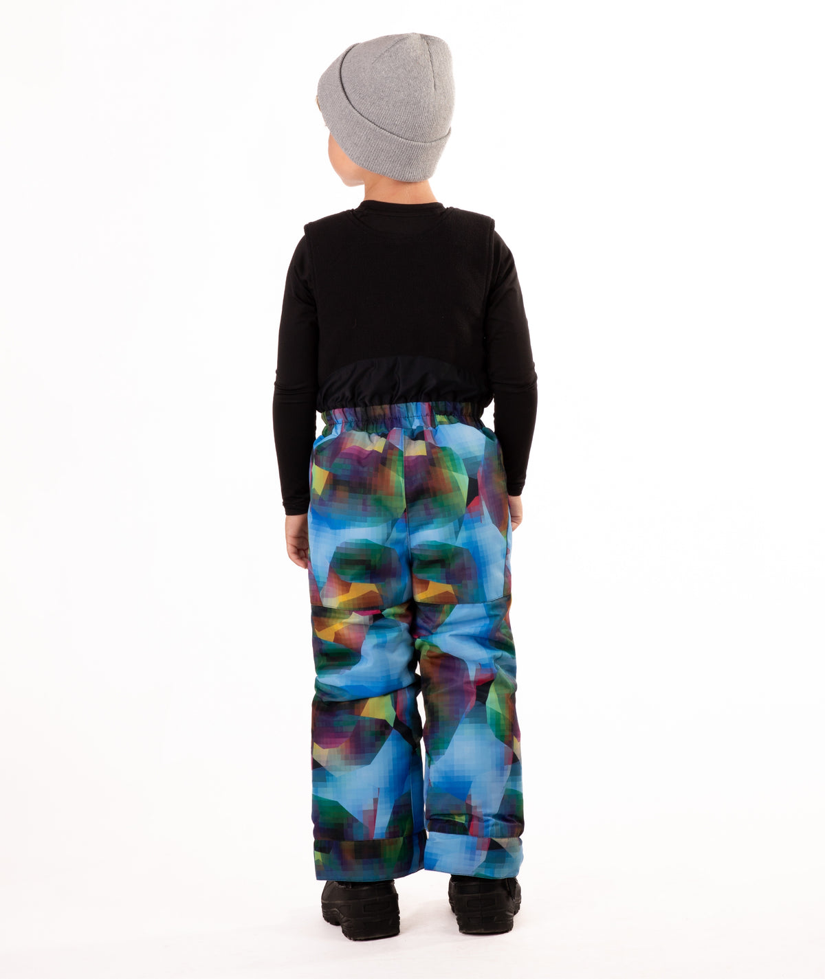 Child wearing colorful geometric print snow bibs on a white background highlighting the back of the bib