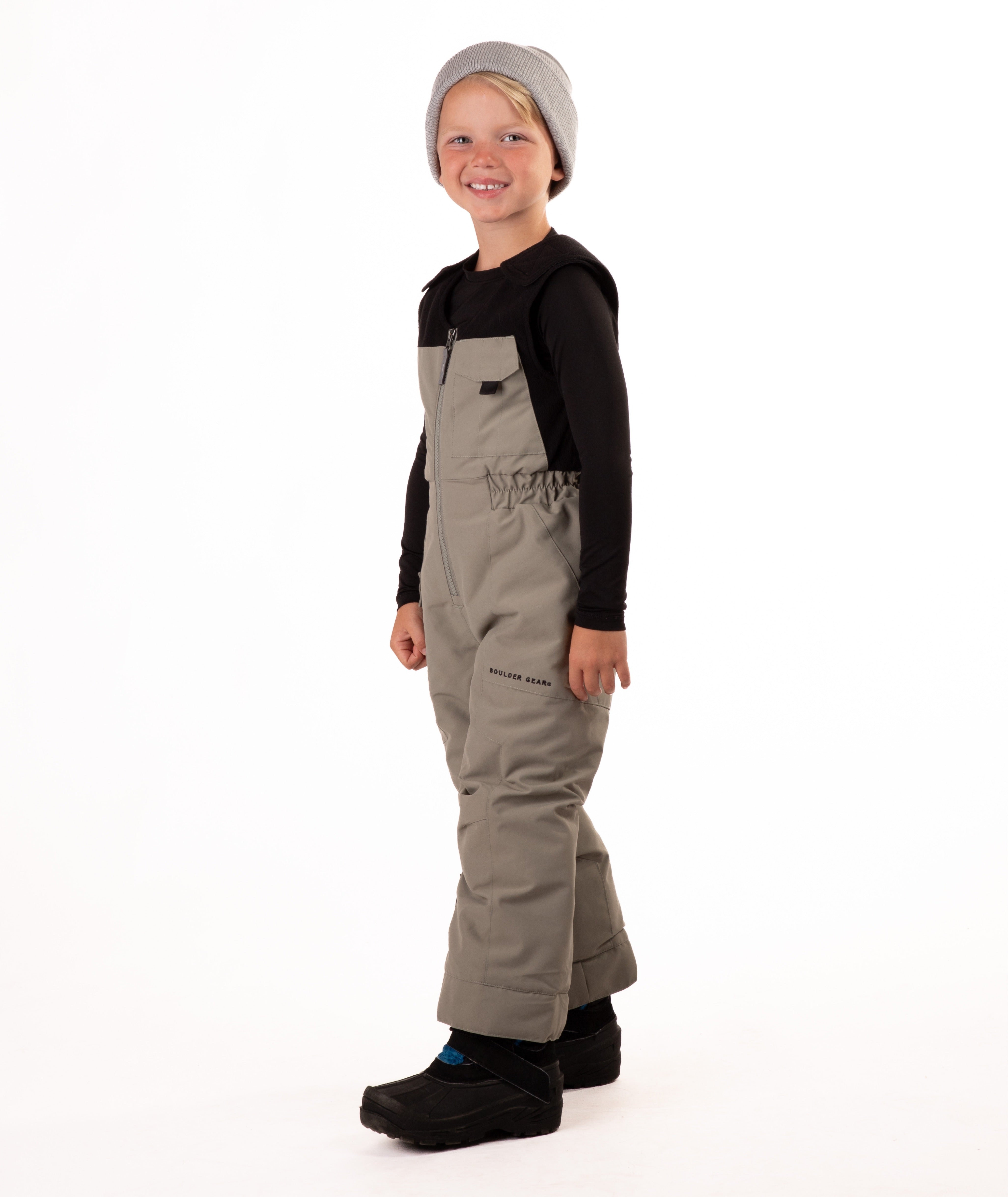 Child wearing beige snow bibs on a white background