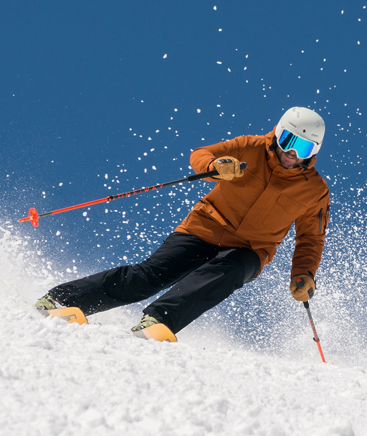 a man skiing on a snowy mountain wearing a rust color insulated jacket